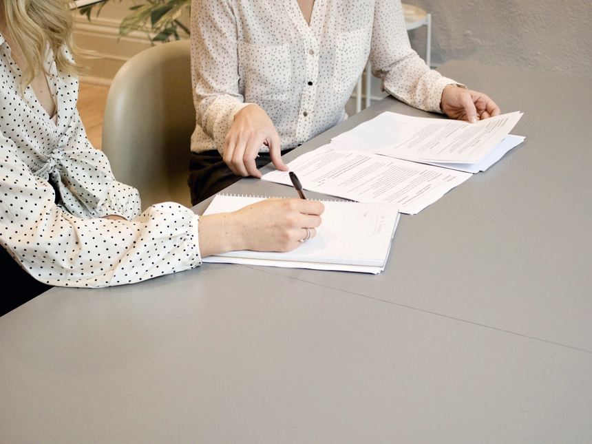 Two people signing finance documents at a table