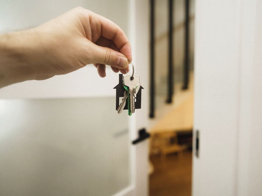 A hand turning a key in the door of a home